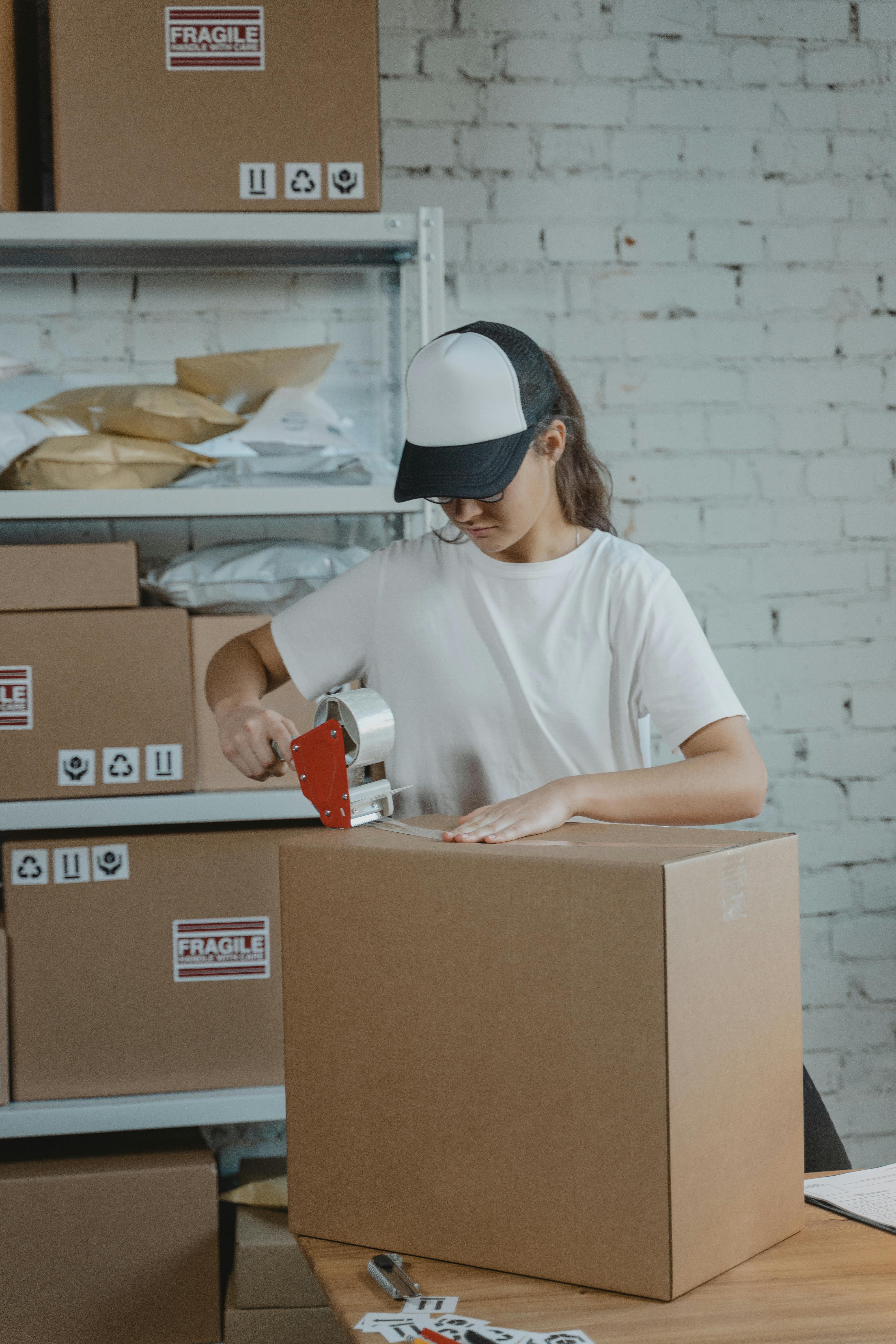 Employee sealing a cardboard box with tape in a warehouse, symbolising fulfilment operations